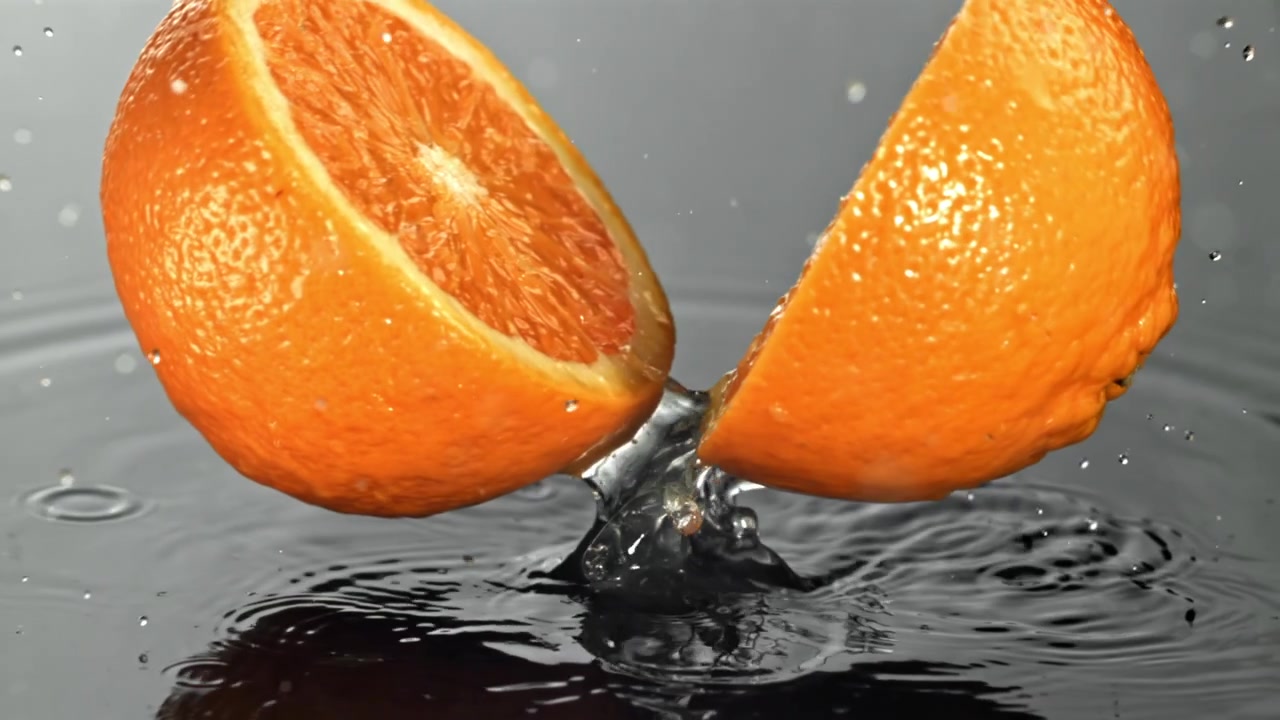 Movimento rallentato di mezze arance fresche che schizzano nell'acqua