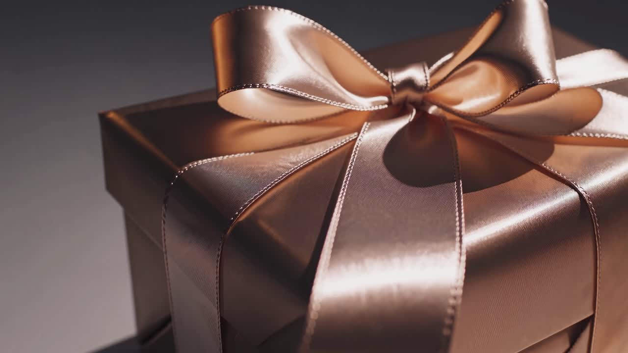 Primo piano di una scatola regalo elegantemente incartata con un nastro di raso, che ne esalta il lusso.