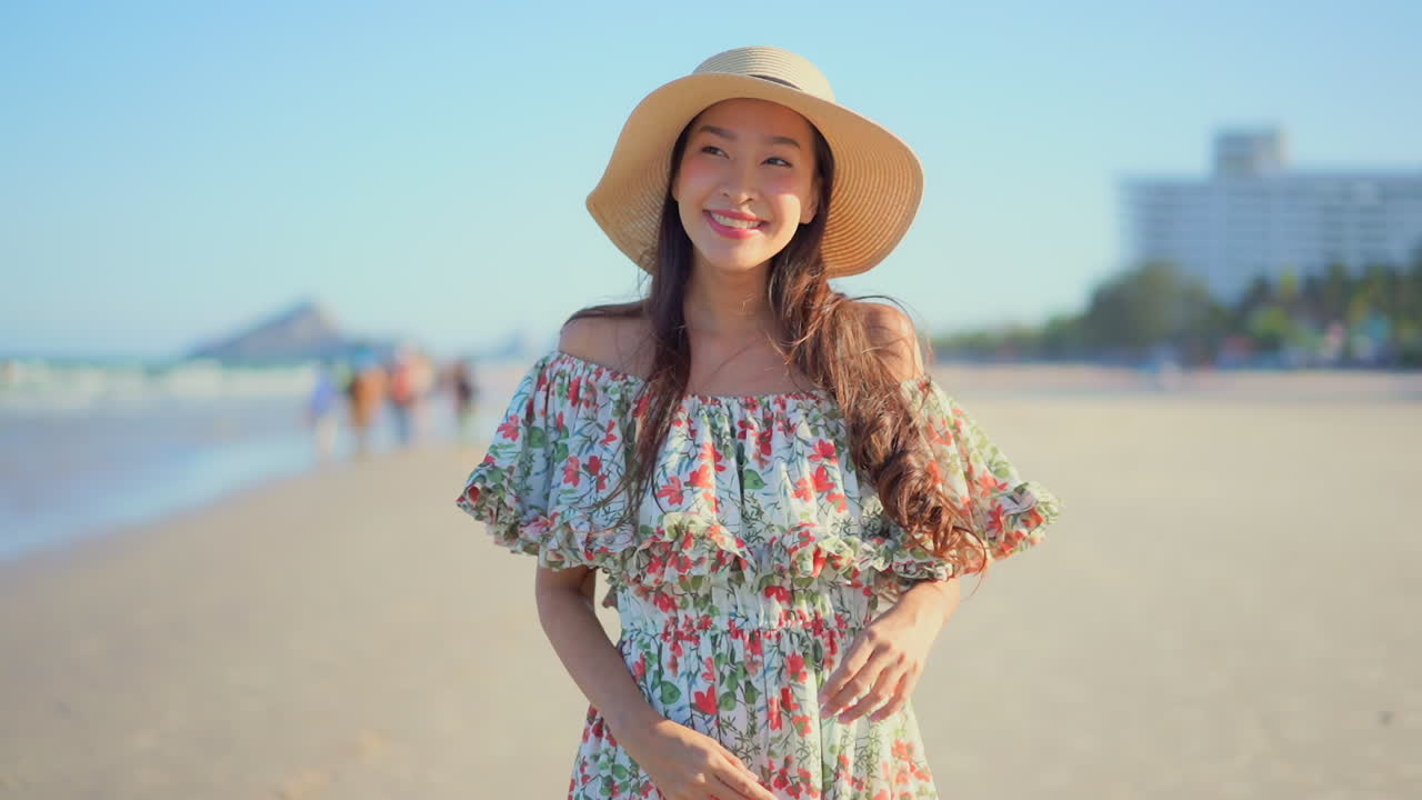 Close-up narrow depth of field, Pretty young Asian woman in a bohemian flower dress stands on the beach smiling enjoying the ocean breeze