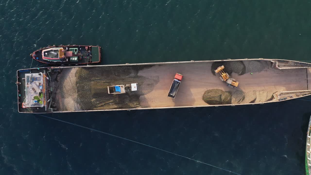 필리핀 항구에서 벌크선에 모래를 싣고 있는 트럭과 로더