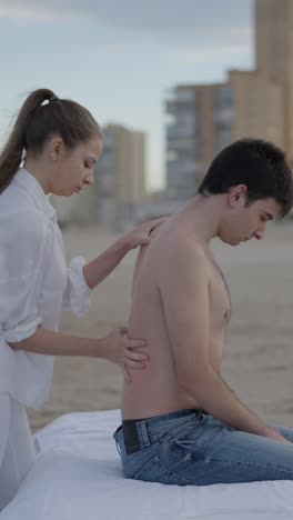 woman giving a back massage to a man on the beach