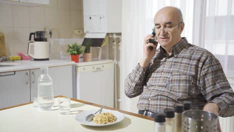 un anciano hablando por teléfono en la cocina.