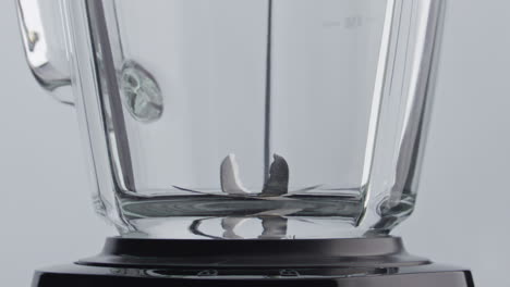 closeup blender blades spinning inside empty glass bowl in super slow motion.