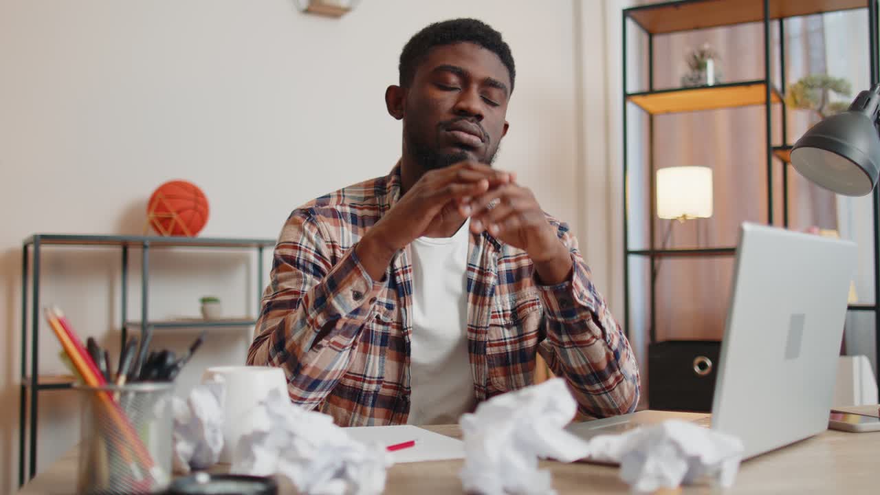Angry furious man working at home office throwing crumpled paper having nervous breakdown at work