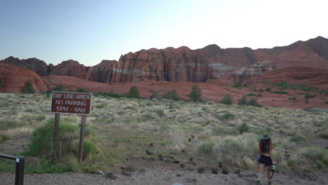 mujer joven con cámara de fotos pasando cantar en la ruta de senderismo de flujo de lava, utah, ee.uu.