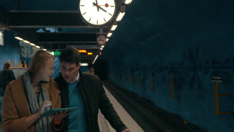 Two-commuters-using-tablet-PC-at-metro-station