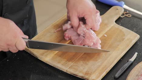 cutting raw meat on a wooden cutting board