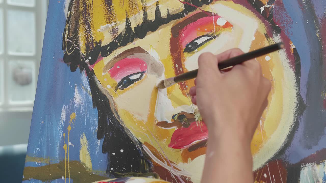 cerca de una mano sosteniendo un pincel y mezclándolo con color antes de pintar la nariz de una chica en el lienzo