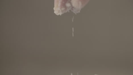 Close up slowmotion shot of a male hand dropping some salt on top of baking flour while moving his fingers LOG