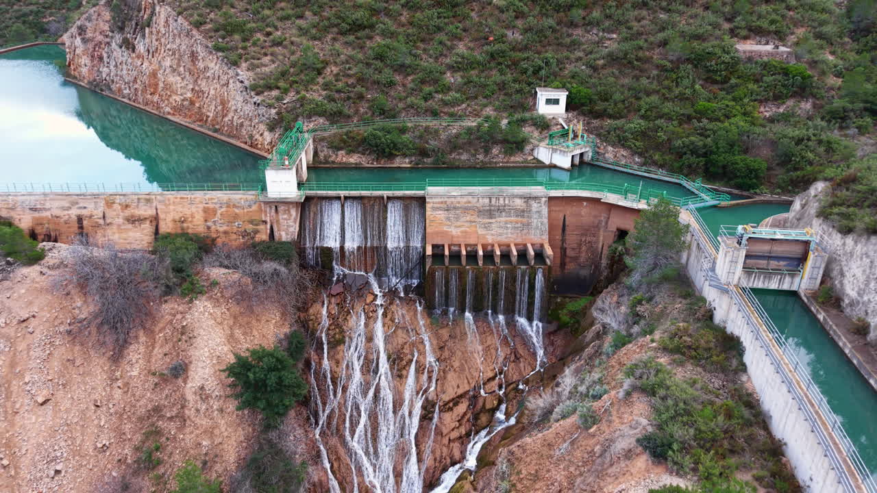 Cascada Domeno baraj savaklarından kayalık kanyona su salınımı, Valensiya bölgesi, İspanya — engebeli tepeler arasına yerleşmiş turkuaz renkli rezervuar.