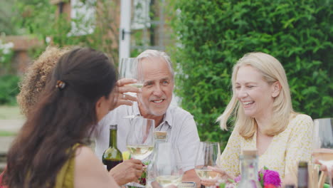 Eine-Gruppe-Reifer-Freunde-Unterhält-Sich-Und-Stößt-Mit-Wein-Auf-Einer-Sommerparty-Im-Heimischen-Garten-An