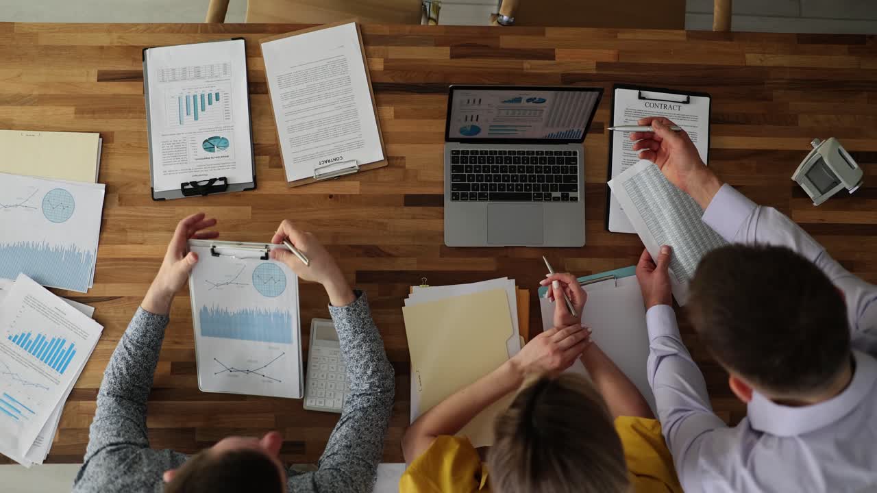 Overhead view of a business team collaborating on financial documents and laptops at a conference table