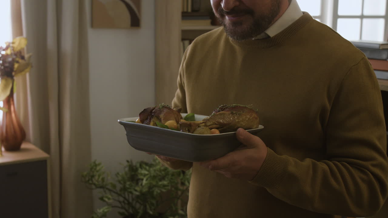 Man holding a platter with roasted chicken
