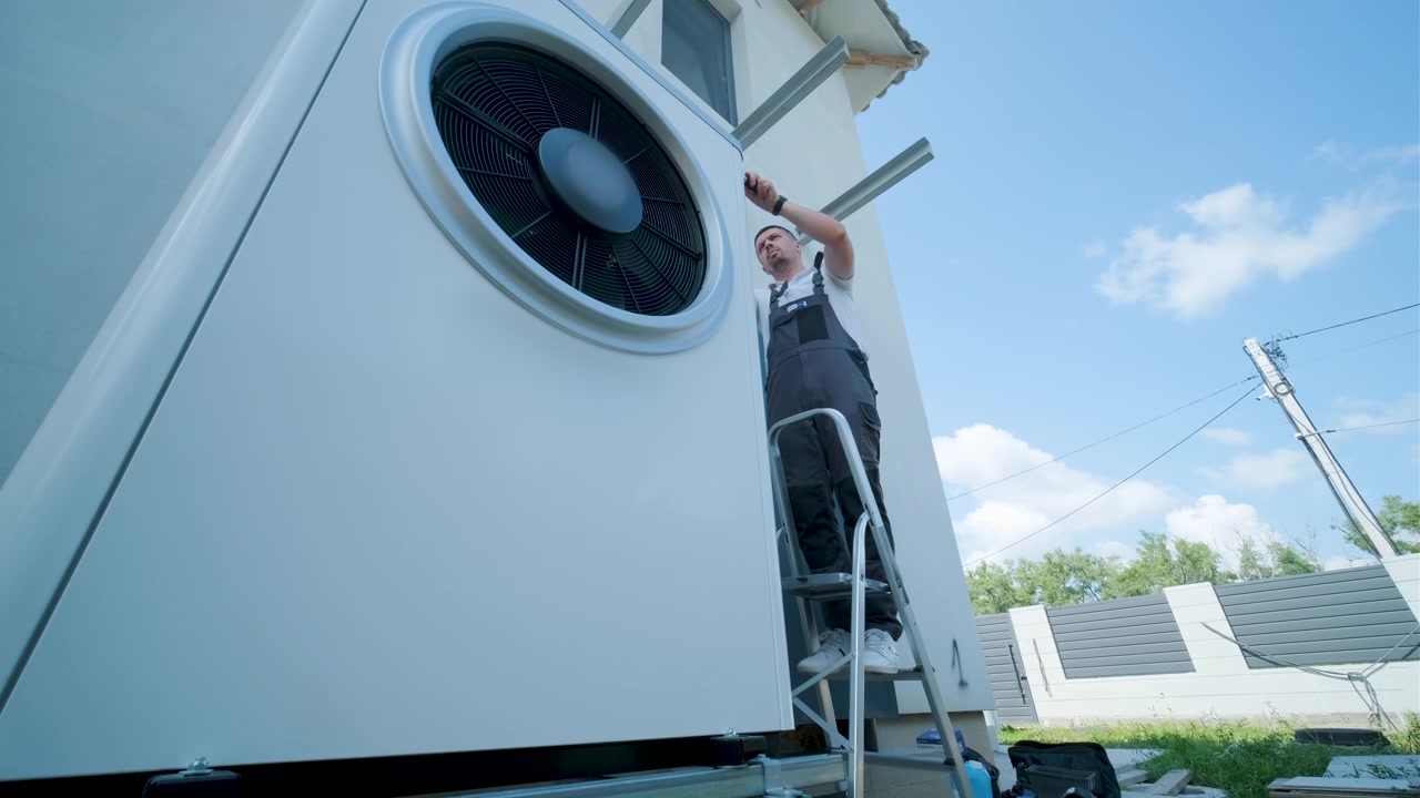 Technician Installing Heat Pump Unit on Residential Exterior Wall