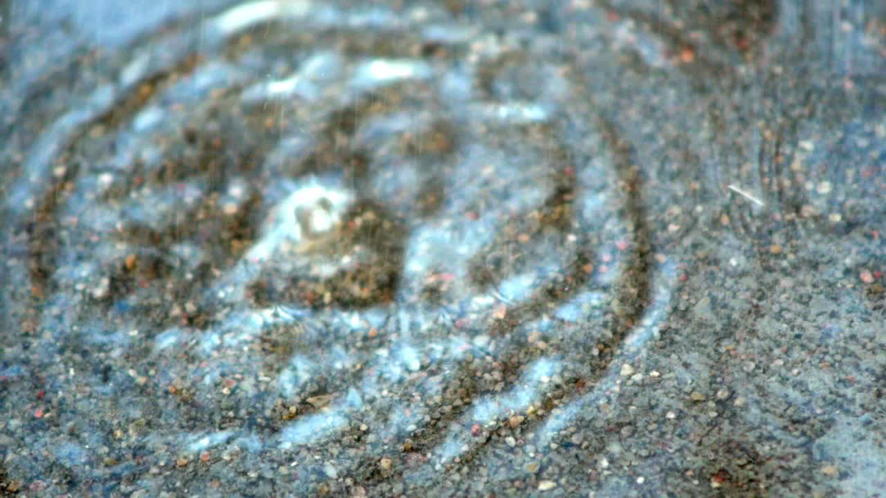 las gotas de lluvia caen al agua en la carretera de hormigón y se salpican