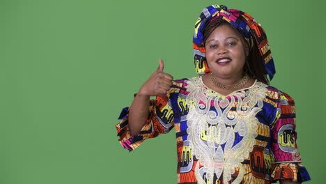 una hermosa mujer africana con sobrepeso que lleva ropa tradicional contra un fondo verde