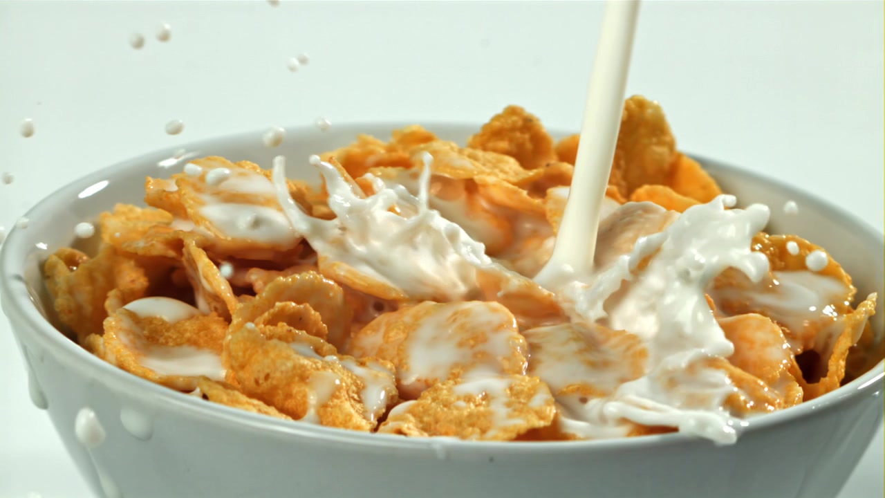 Frisk mælk hældes over gyldne cornflakes