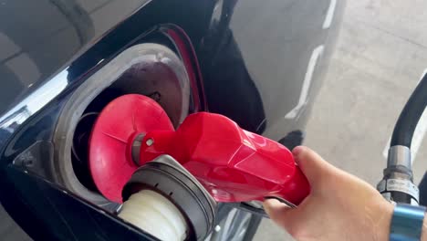 close-up of male hand refueling a black car with expensive gas oil prices