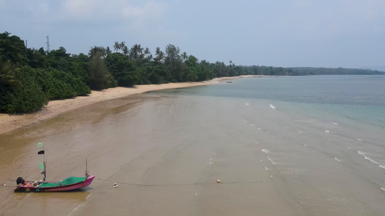 vista aérea volando a lo largo de la playa vacía de ao kao en koh mak más allá de un barco de pesca solitario amarrado en la arena