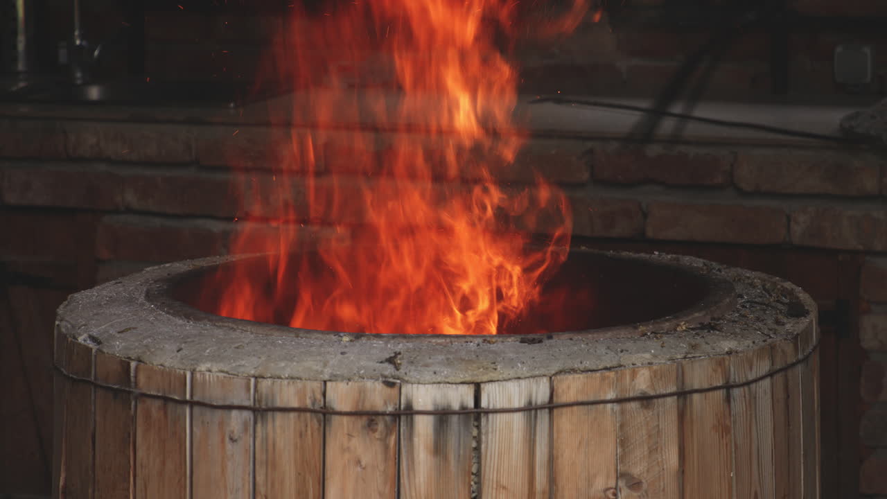 panadero sosteniendo una pala de horquilla quemando madera en un horno redondo rústico tradicional para hornear pan en sighnaghi, kakheti, georgia