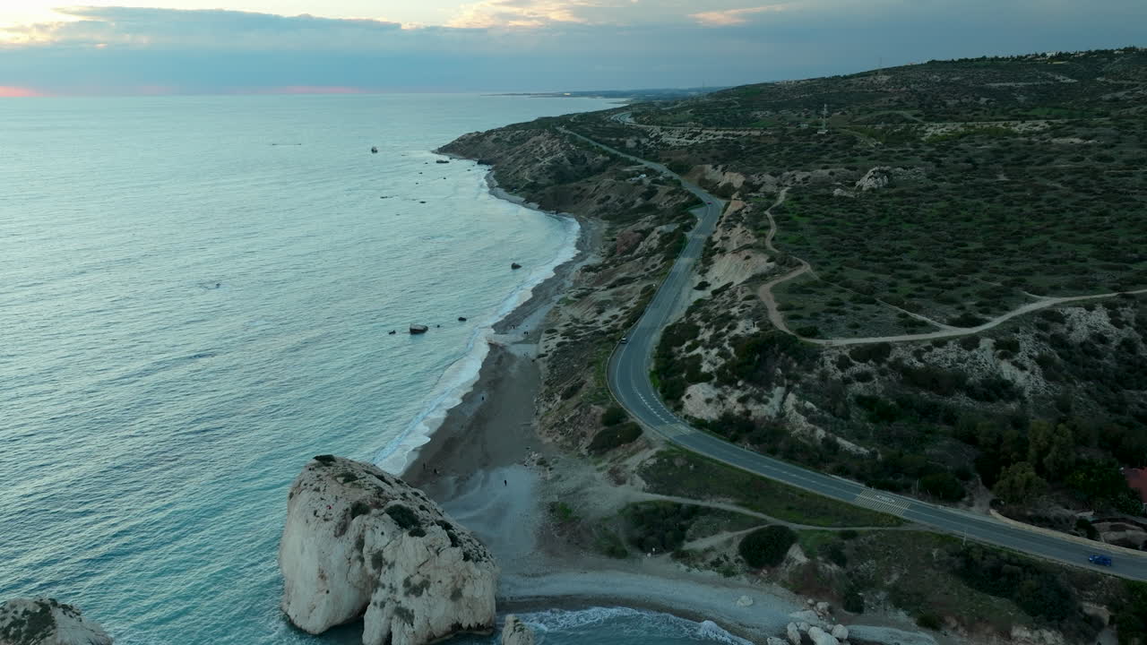 carretera sinuosa a lo largo de la costa de la isla de chipre con colorido atardecer en el fondo - retiro aéreo