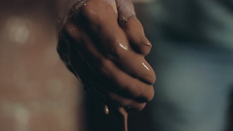 hand of a worker with brown wet mud clay at workshop in antigua, guatemala