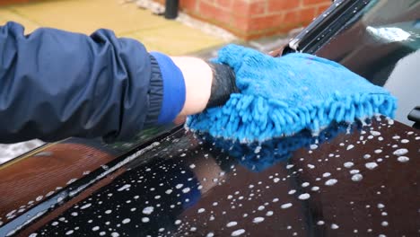 washing black car bonnet hood with microfibre noodle mitt