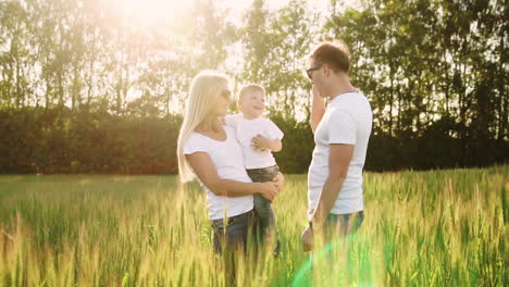 young parents go to the field with spikelets of wheat in white t-shirts and jeans