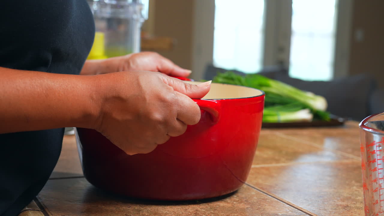 un ama de casa coloca un horno holandés de esmalte lleno en la estufa y luego enciende la llama alimentada por gas en cámara lenta