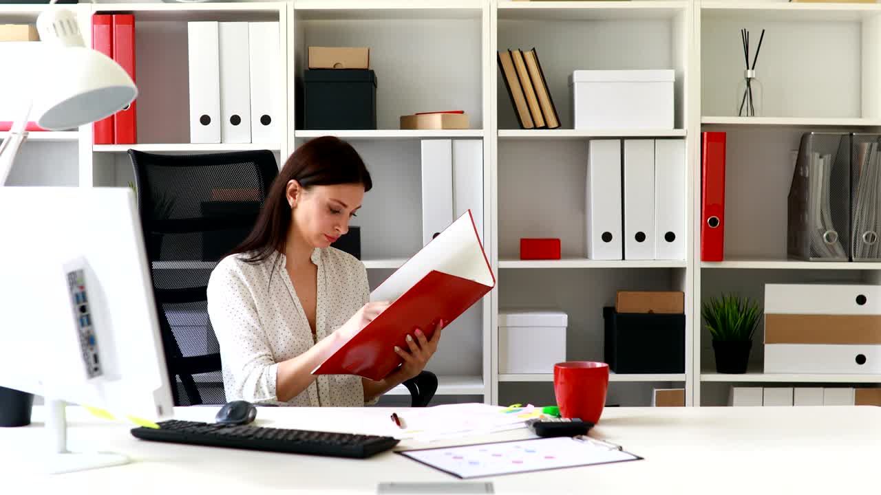 mujer de negocios en blusa blanca examinando documentos en la carpeta