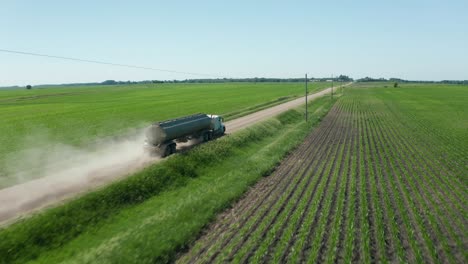 camión aéreo, combustible conduciendo por un camino de tierra sin pavimentar en tierras agrícolas
