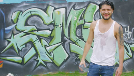 handsome-guy-drinking-fresh-water-from-a-plastic-bottle-in-a-skate-park