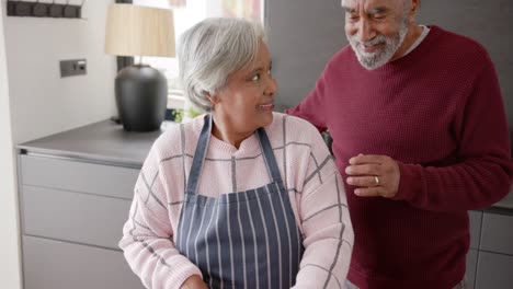 Senior-biracial-couple-cooking-dinner-and-chopping-vegetables-in-kitchen,-unaltered,-in-slow-motion