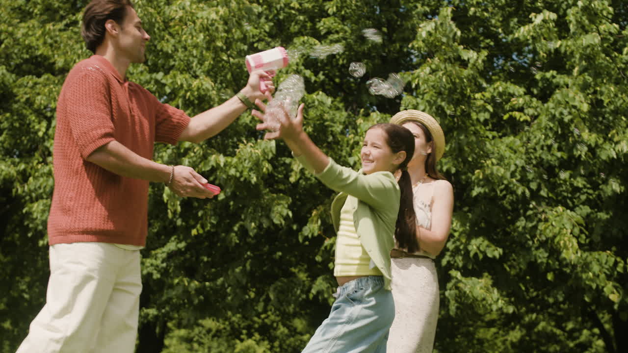familia jugando con burbujas en el parque