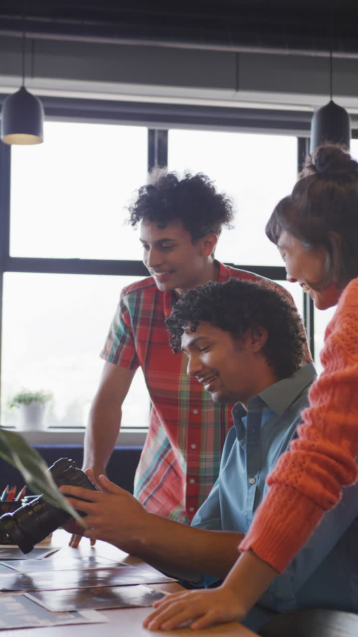 video vertical de personas de negocios felices y diversas discutiendo el trabajo durante una reunión en la oficina