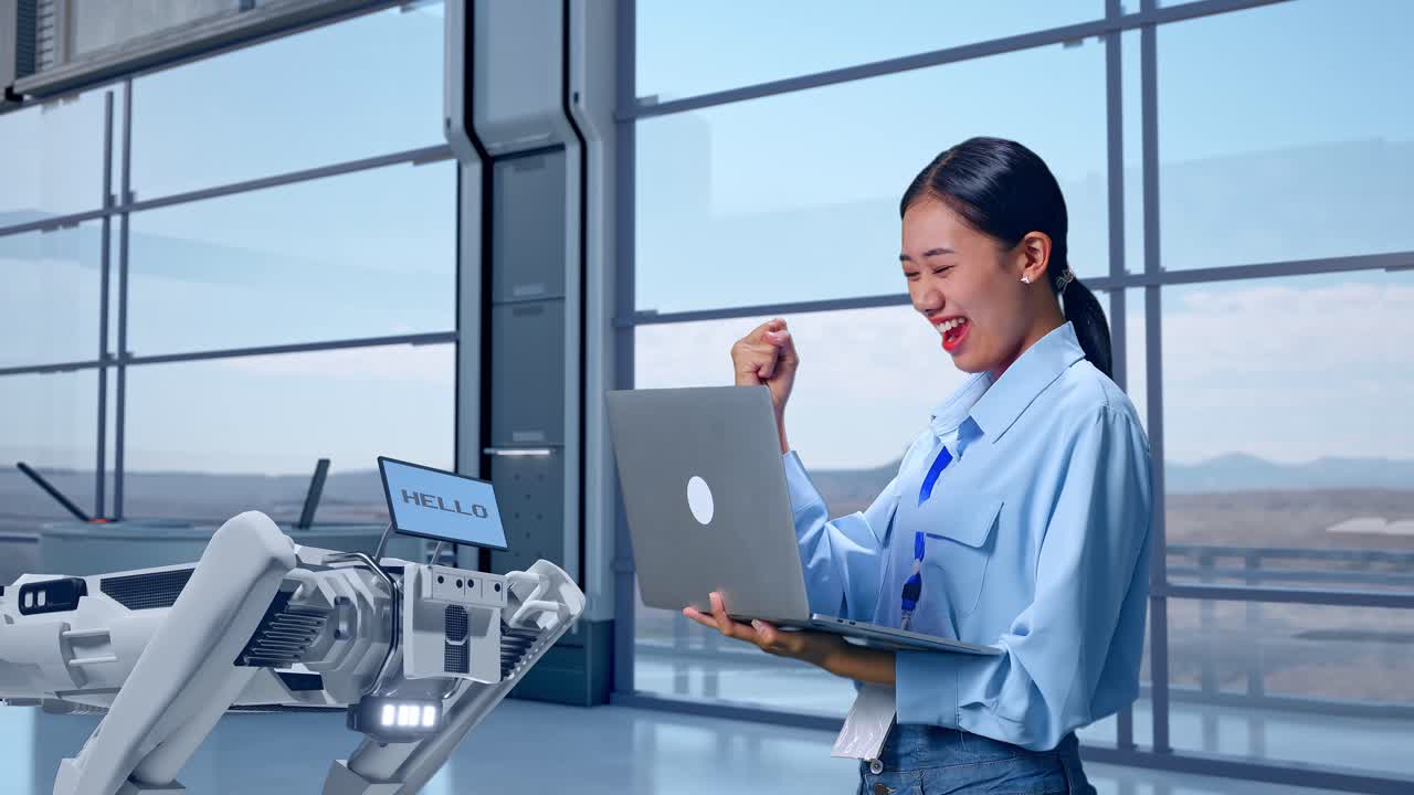 고급 공장에서 노트북을 들고 서 있는 아시아 여성 직원, 로 개, 그녀는 노트북에 타이핑 한 후 소리 지르는 목표로 주먹을 들어 올립니다.