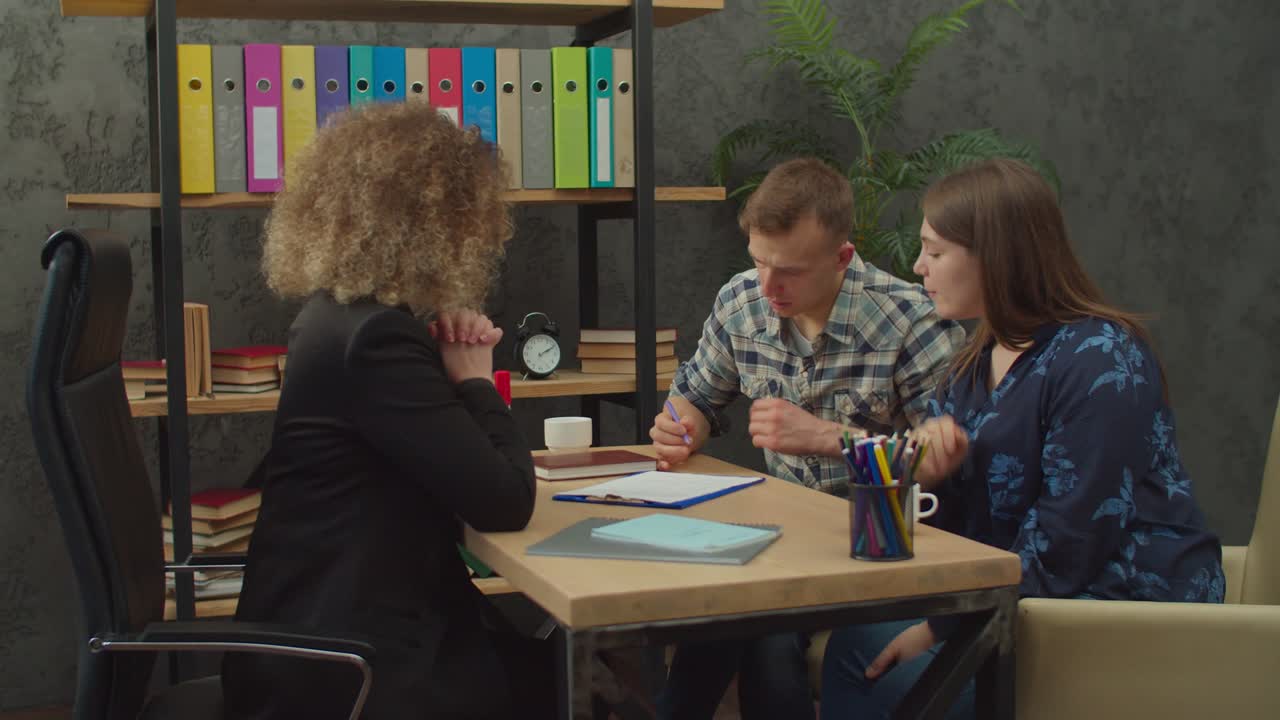 una pareja feliz y una agente inmobiliaria firman un contrato inmobiliario en la oficina.