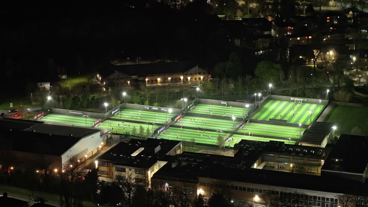 Players practice on football pitches at night in Sheffield, aerial view
