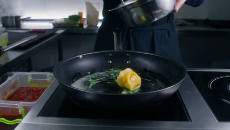 chef cook puts ravioli in frying pan at stove