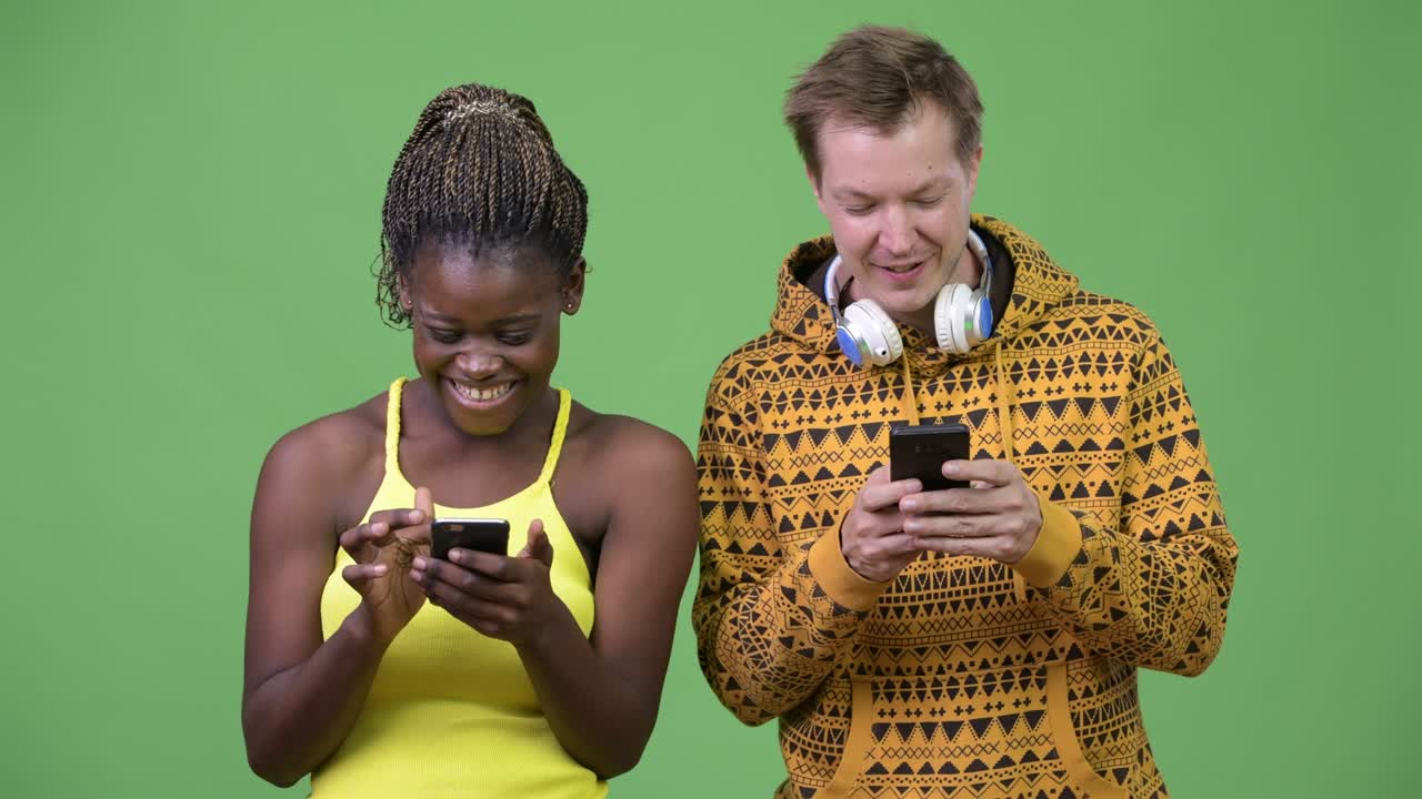 una joven pareja multiétnica usando el teléfono juntos.