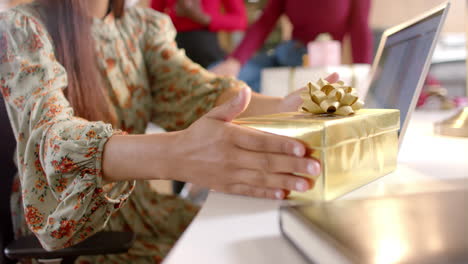 happy diverse female creative colleagues giving christmas presents in office, slow motion