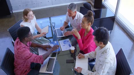 Multi-ethnic-business-colleagues-discussing-over-graphs-in-a-meeting-at-modern-office-4k