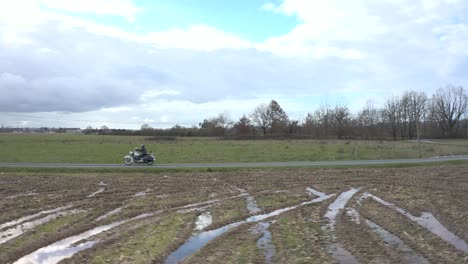 lateral de la antena, ciclista en una motocicleta de época montando a través del campo