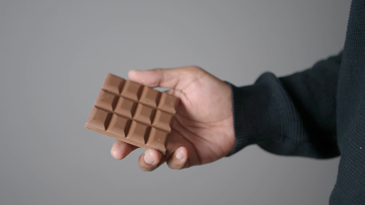 Close-Up of Hand Holding a Bar of Milk Chocolate
