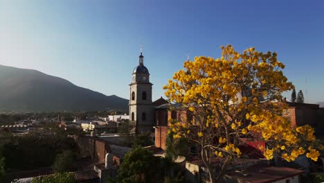 Aerial-revealing-shot-showing-popular-tourist-attraction-of-San-Bautista-Temple-in-Tuxpan-during-golden-sunset---Mountain-silhouette-in-background