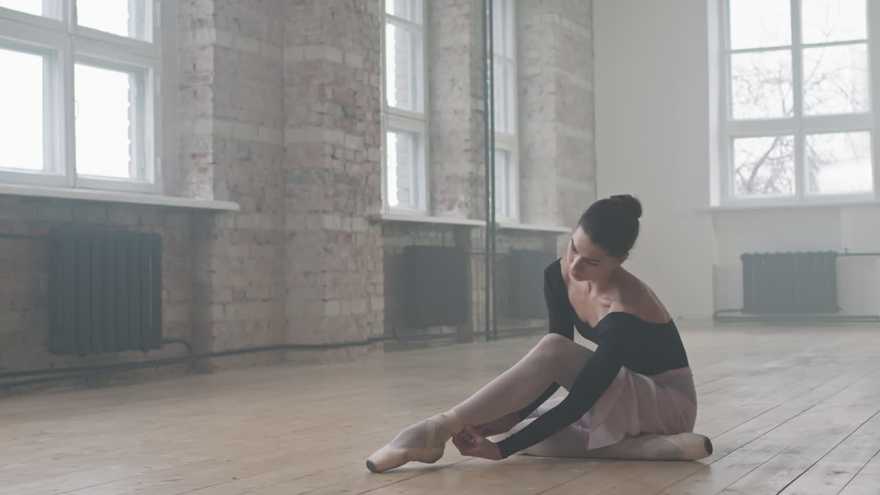 Elegant Ballerina Tying Pointe Shoes On Floor