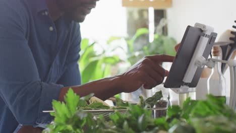 Glücklicher-Afroamerikanischer-Mann,-Der-In-Der-Küche-Das-Abendessen-Kocht-Und-Dabei-Ein-Tablet-Verwendet