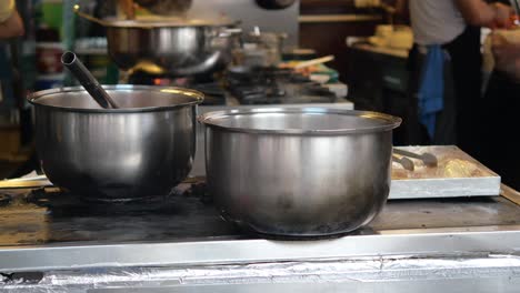 stainless steel pots on a stove in a commercial kitchen