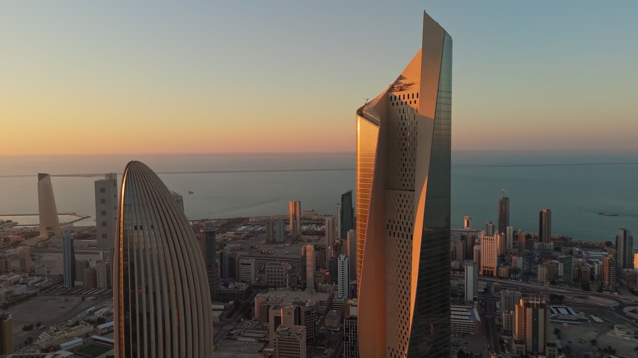 Stunning 4K aerial of Kuwait City at sunrise. Iconic skyscrapers glowing in golden light over the Arabian Gulf. Perfect for real estate, tourism, or cinematic B-roll.