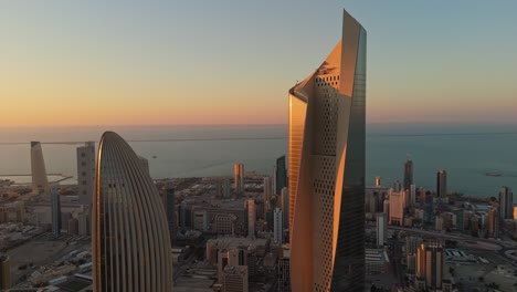 stunning 4k aerial of kuwait city at sunrise. iconic skyscrapers glowing in golden light over the arabian gulf. perfect for real estate, tourism, or cinematic b-roll.